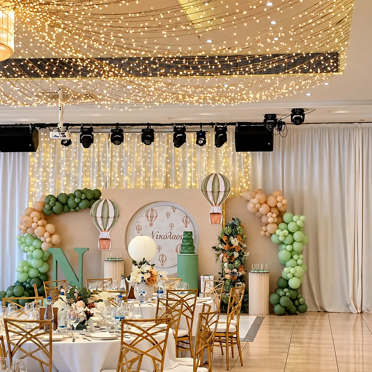 A ballroom christening with sage green styling, a themed backdrop and fairy lights along the walls
