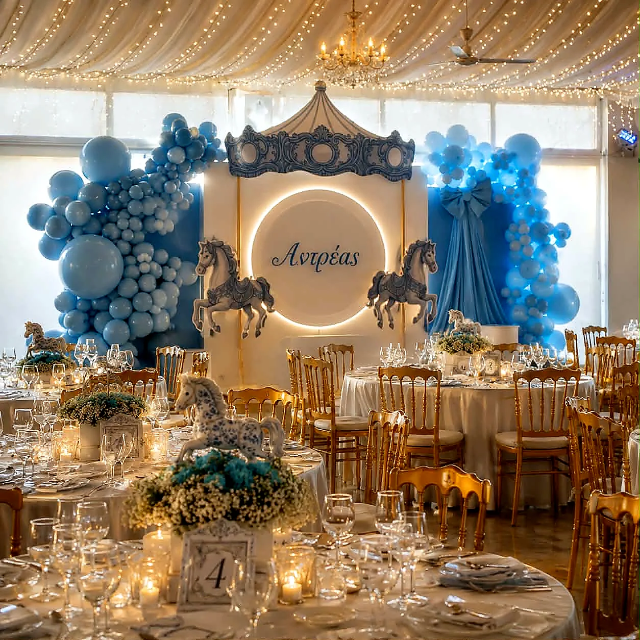 A blue and white christening reception with balloon garlands and a painted carousel backdrop