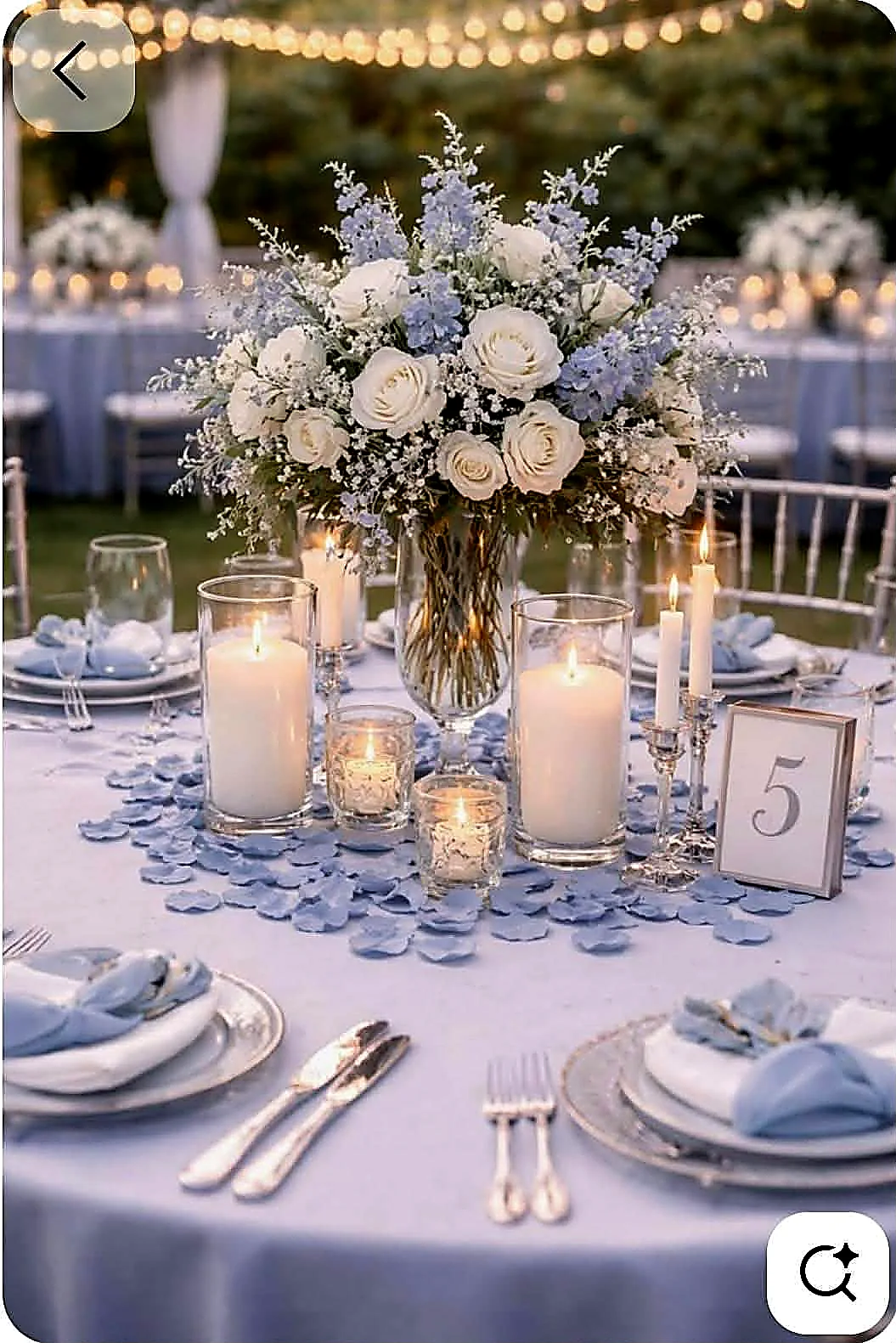 A table setting in pale blue and white with candles, glassware and a low floral centrepiece