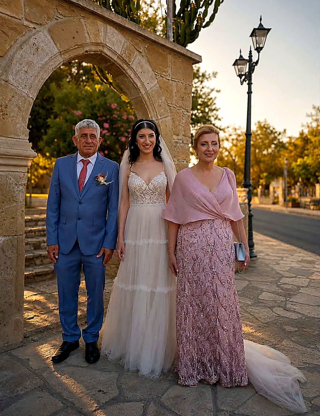 A bride photographed with her family beneath a stone arch after the ceremony