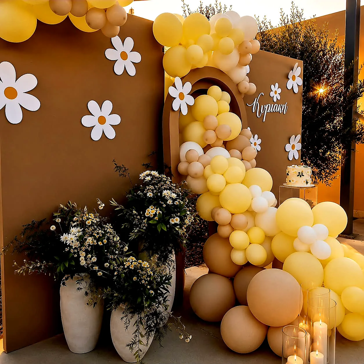 A christening backdrop in butter yellow and cream with an oversized daisy balloon garland