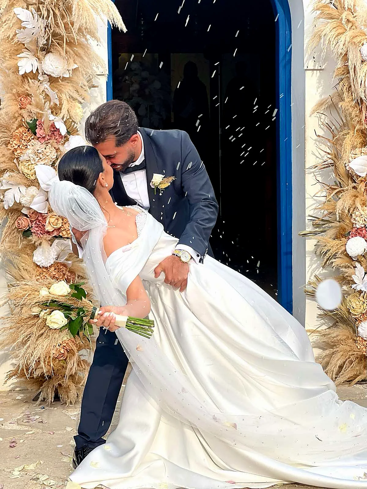 A couple dancing in a doorway framed with pampas grass and dried florals