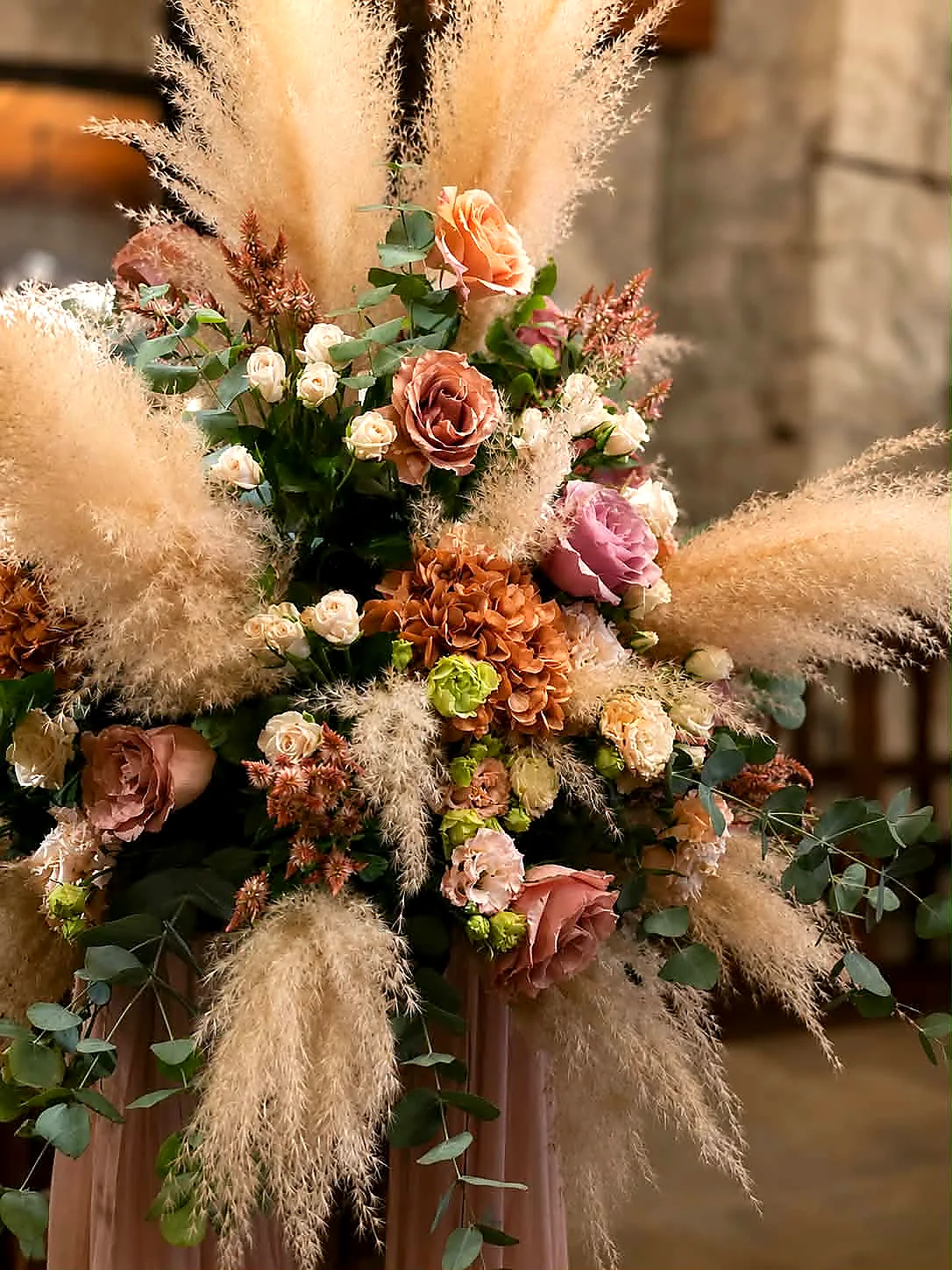 Close view of a tall arrangement of pampas grass, garden roses and dried florals in cream and blush