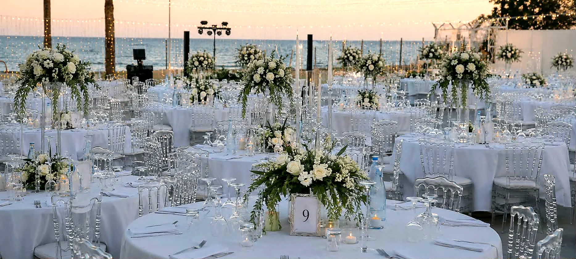 Banquet tables with tall white floral centrepieces overlooking the sea