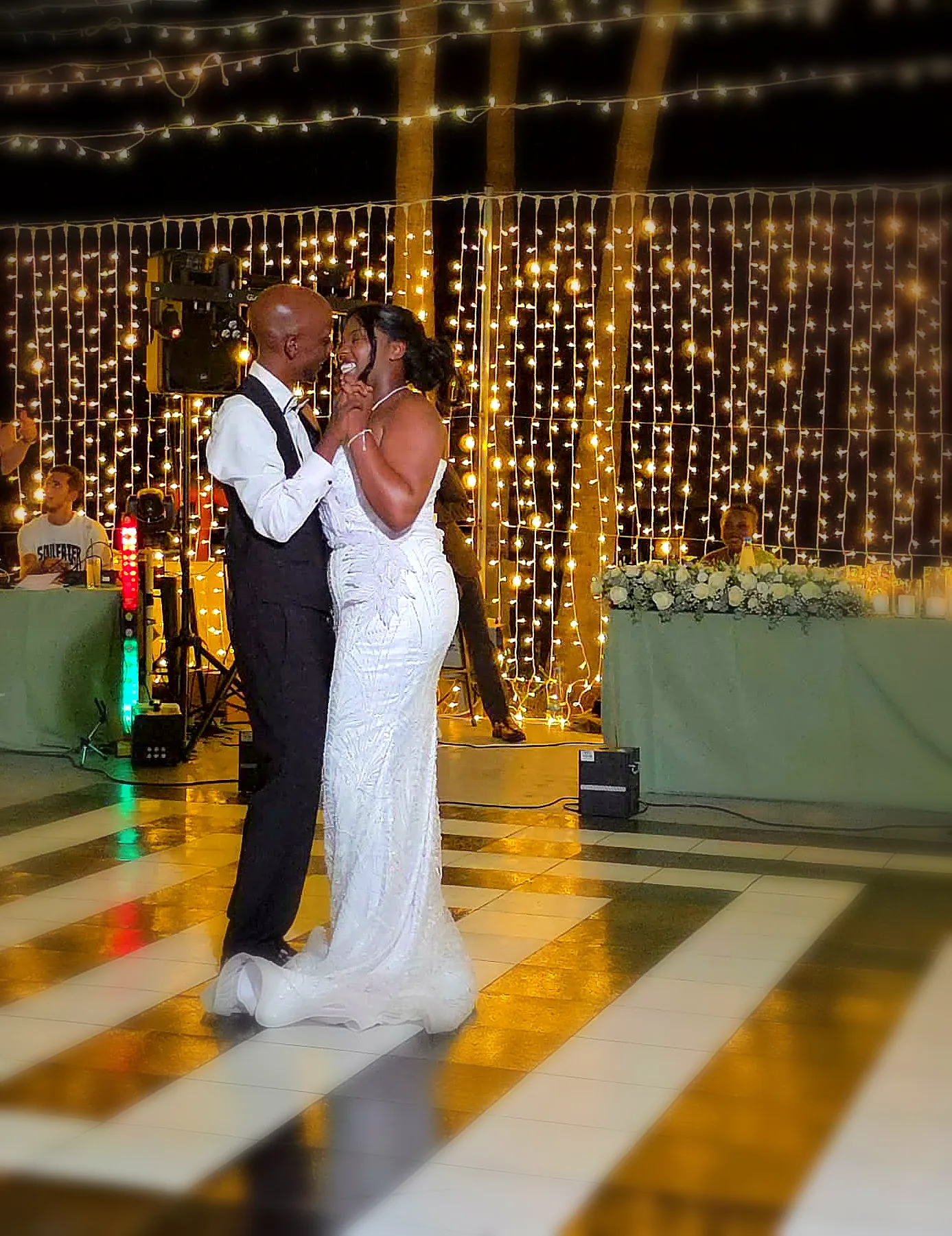 A couple sharing their first dance beneath a curtain of warm lights